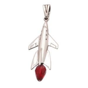 May include: A silver rocket ship pendant with a red crystal at the end. The rocket ship is detailed with a pointed nose and wings.