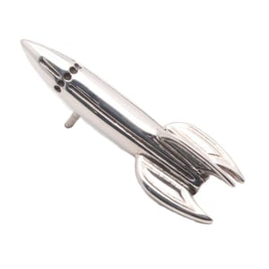 May include: A silver rocket ship figurine with a pointed nose and fins. The rocket has a detailed design with lines and a small hole at the top.