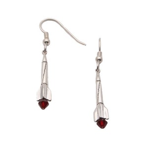 May include: A pair of silver earrings with a red gem at the bottom of each earring. The earrings are shaped like a rocket.