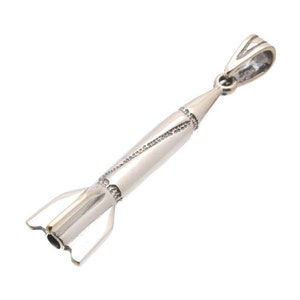 May include: A silver-colored rocket pendant with a detailed design. The pendant features a cylindrical body, a pointed nose cone, and fins at the base. The bail is a simple loop for attaching to a chain. The rocket is made of a shiny metal.