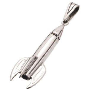 May include: A silver rocket ship pendant charm. The charm is detailed with a pointed nose and fins.