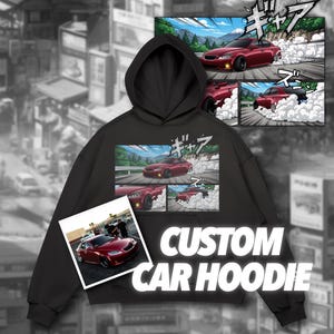 May include: Black hoodie with a custom car design. The design features a red car in a comic book style, with the text "CUSTOM CAR HOODIE" in white. The background is a blurred cityscape.