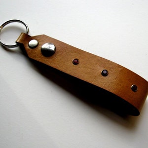 May include: A brown leather keychain with a silver ring and four red gemstones.
