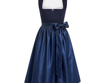 May include: A dark navy blue dirndl dress featuring a square neckline with a white inner lining, a fitted bodice, and a full, knee-length skirt. The waist is accented with a matching dark navy blue satin ribbon tied into a bow at the front center.