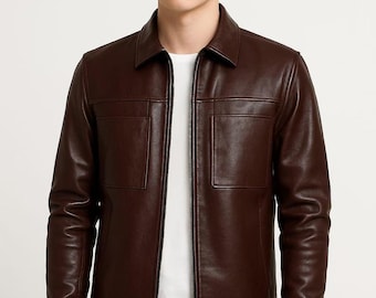 Könnte beinhalten: Braune Lederjacke mit Kragen und zwei Vordertaschen. Die Jacke hat einen durchgehenden Reißverschluss und wird über einem weißen T-Shirt getragen. Das Model trägt eine schwarze Hose.