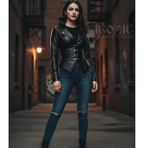 May include: A black leather jacket with a unique design, featuring a high collar and a series of small buttons down the front. The jacket is worn with blue jeans. The text "ICONIC LEATHER HUB" is visible in the background.