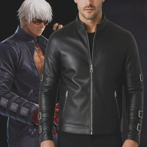 Op de afbeelding: Een zwarte leren jas met een opstaande kraag en een lange ritssluiting. De jas heeft twee zakken met ritssluiting op de borst en twee aan de zijkanten. De mouwen hebben een banddetail bij de manchetten. Een personage in een blauwe jas staat op de achtergrond.