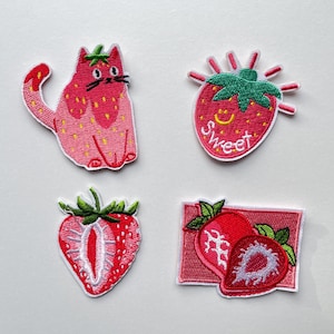 Könnte beinhalten: Vier gestickte Aufnäher mit Erdbeermotiv. Einer ist eine rosa Katze mit Erdbeerdetails. Ein weiterer ist eine rote Erdbeere mit dem Wort "Sweet". Die anderen beiden Aufnäher sind Erdbeeren.