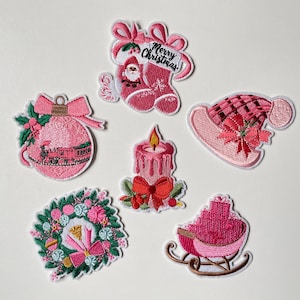 Peut inclure: Ensemble de patchs de Noël brodés roses. Ils représentent une chaussette avec le Père Noël, un train sur une boule, une bougie, une couronne, un chapeau et une luge. Le patch de la chaussette porte l'inscription "Merry Christmas".