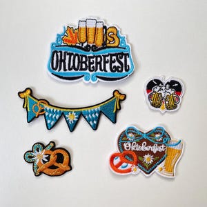 Könnte beinhalten: Ein Set aus fünf bestickten Aufnähern zum Thema Oktoberfest. Das Set enthält ein großes Schild mit Bierkrügen, eine blau-weiße Wimpelkette, einen herzförmigen Aufnäher mit Bier und Brezel, eine kleine Brezel sowie ein Herz mit zwei Bierkrügen.