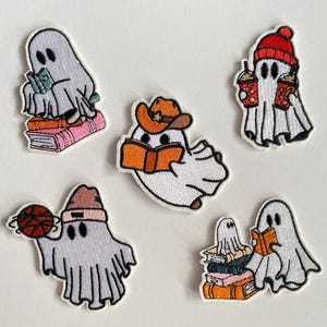 Può includere: Toppe ricamate raffiguranti fantasmi dei cartoni animati in varie pose. Un fantasma legge sopra i libri, un altro indossa un cappello da cowboy e legge, e un altro tiene in mano un caffè freddo. Altri fantasmi tengono in mano un pallone da basket e leggono un libro.