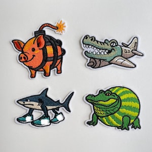 Könnte beinhalten: Vier gestickte Aufnäher mit skurrilen Tierdesigns. Enthält ein Schwein im Bombenkostüm, ein Alligator mit einem Flugzeug, ein Hai mit Turnschuhen und ein Alligator im Wassermelonen-Kostüm. Ideal zum Aufnähen auf Kleidung oder Accessoires.