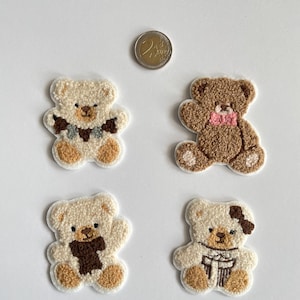 Pode incluir: Quatro patches bordados de ursinhos de pel&uacute;cia em tons de creme e castanho. Cada urso tem um detalhe &uacute;nico de cachecol ou la&ccedil;o. Uma moeda de dois euros est&aacute; inclu&iacute;da para refer&ecirc;ncia de tamanho. Os patches est&atilde;o em um fundo branco.