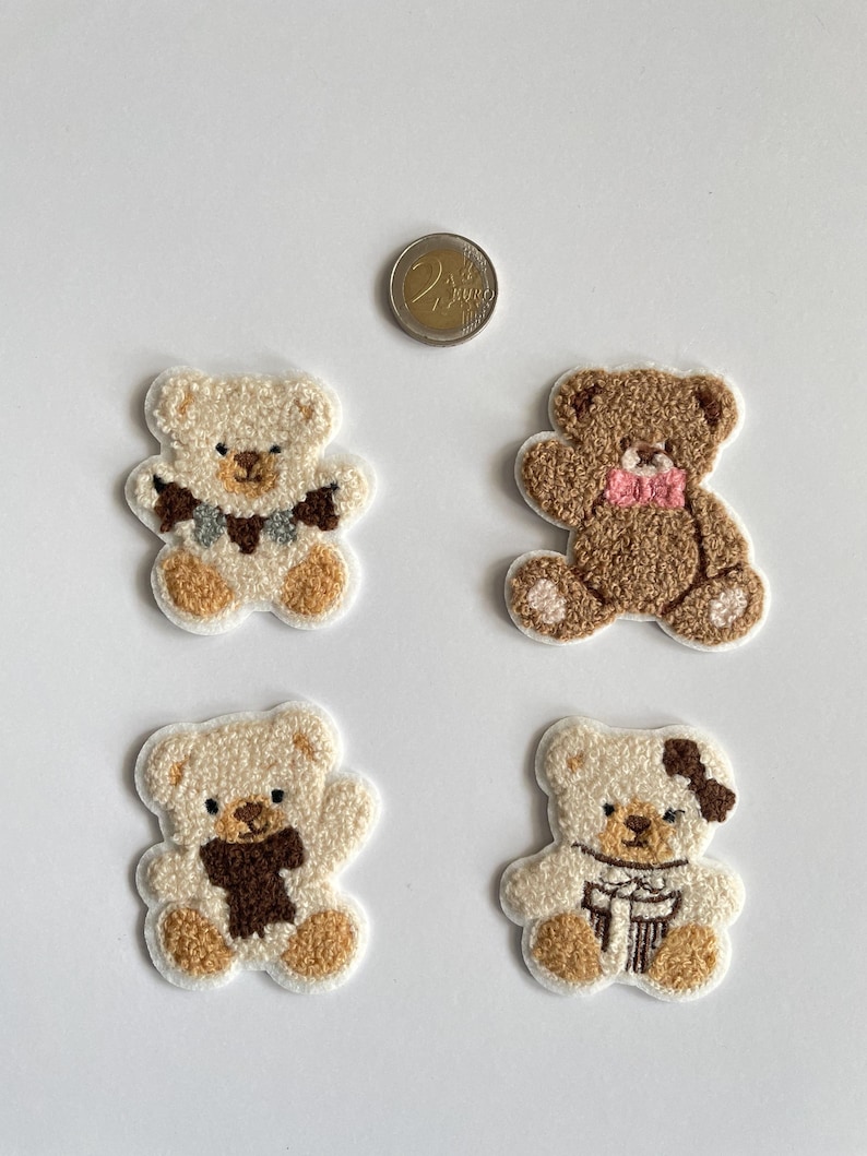 Pode incluir: Quatro patches bordados de ursinhos de pel&uacute;cia em tons de creme e castanho. Cada urso tem um detalhe &uacute;nico de cachecol ou la&ccedil;o. Uma moeda de dois euros est&aacute; inclu&iacute;da para refer&ecirc;ncia de tamanho. Os patches est&atilde;o em um fundo branco.