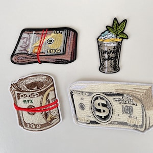 Könnte beinhalten: Gestickte Aufnäher mit Geldbündeln zu 100 $, einem gerollten Geldbündel und einem Cocktail mit Cannabisblatt-Garnitur. Die Aufnäher sind in Grün, Braun und Rot gehalten.