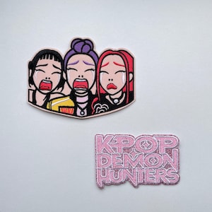 Könnte beinhalten: Zwei aufgestickte Aufnäher. Einer zeigt drei weinende Cartoon-Frauen mit offenem Mund. Der andere Aufnäher hat den Text "KPOP DEMON HUNTERS" in rosa Glitzer.