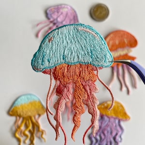 May include: Embroidered jellyfish patches in various colors, including blue, orange, yellow, and purple. The patches feature detailed stitching and flowing tentacles, perfect for adding a unique touch to clothing or accessories.