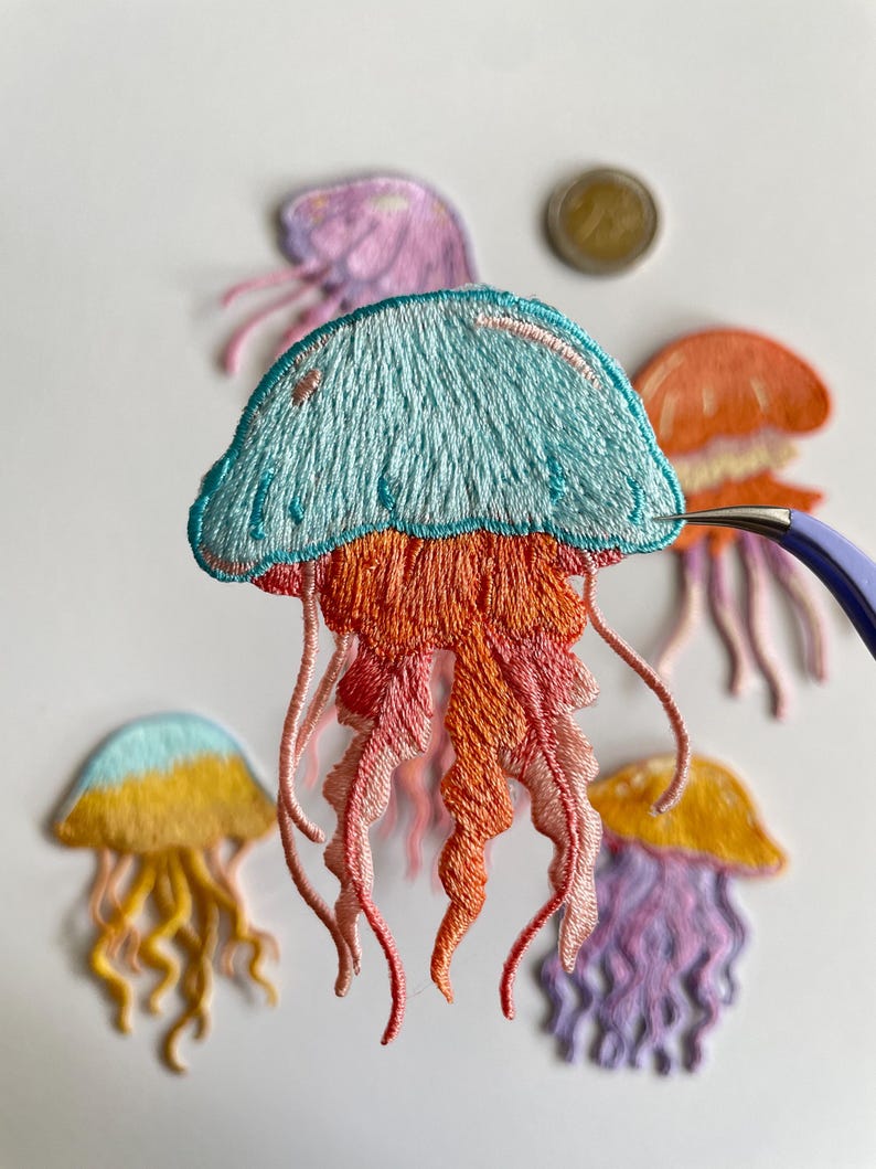 May include: Embroidered jellyfish patches in various colors, including blue, orange, yellow, and purple. The patches feature detailed stitching and flowing tentacles, perfect for adding a unique touch to clothing or accessories.