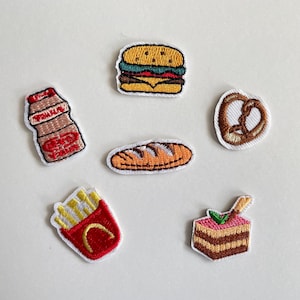 Può includere: Toppe ricamate con cibo, tra cui un hamburger, un pretzel, una pagnotta, patatine fritte, una torta a strati e una bottiglia di bevanda. Le toppe presentano cuciture dettagliate e colori vivaci, per abbigliamento o accessori.