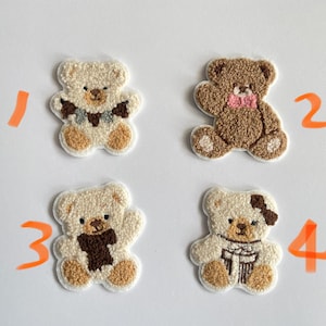 Pode incluir: Quatro patches bordados de ursinhos de pel&uacute;cia em v&aacute;rias cores. Dois s&atilde;o creme com detalhes marrons, e dois s&atilde;o marrons. Cada urso tem um cachecol ou la&ccedil;o diferente. Ideal para projetos de artesanato.