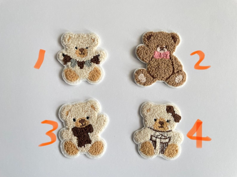 Pode incluir: Quatro patches bordados de ursinhos de pel&uacute;cia em v&aacute;rias cores. Dois s&atilde;o creme com detalhes marrons, e dois s&atilde;o marrons. Cada urso tem um cachecol ou la&ccedil;o diferente. Ideal para projetos de artesanato.
