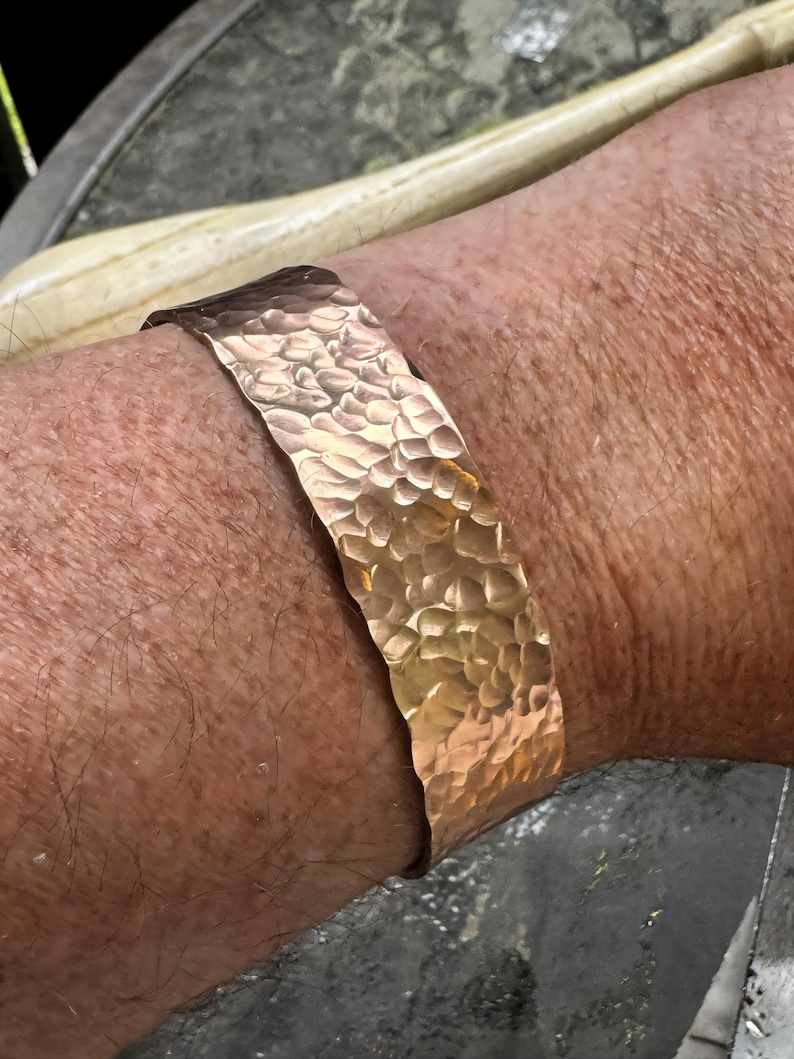 Puede incluir: Un brazalete de cobre martillado. El brazalete tiene una superficie texturizada con un dise&ntilde;o martillado. El brazalete mide aproximadamente 3,8 cm de ancho.