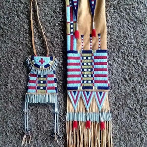 May include: Two beaded Native American crafts. One is a small, rectangular pouch with a leather strap. The other is a larger, rectangular piece with a tan suede backing, red, blue, and white beadwork, and fringe.