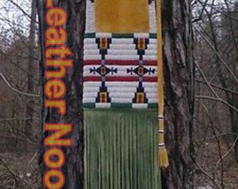May include: A handcrafted leather bag with a yellow suede top and a beaded design in red, white, blue, and green. The bag has long green fringe and the text "Leather Nook" in orange.
