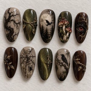 May include: A set of ten almond-shaped press-on nails featuring dark, nature-inspired designs including a bare tree, a moonlit forest with a raven, mushrooms, a spider web with a spider, a red eye, and metallic gold vine accents on brown and green.