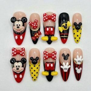 May include: A set of ten artificial nails with a Disney theme. The nails feature Mickey Mouse and Minnie Mouse designs, including bows, polka dots, and character faces. Colors include red, black, yellow, and white.