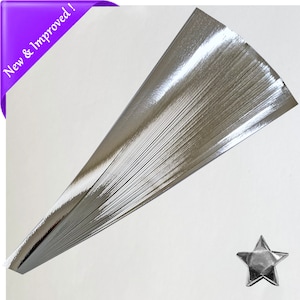 Puede incluir: Una pila de tiras de papel de origami plateado. El papel es brillante y tiene un acabado met&aacute;lico. Una estrella de origami plateada se muestra en la esquina inferior derecha de la imagen.