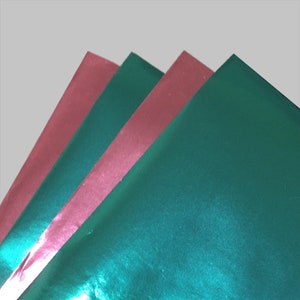 Puede incluir: Cuatro hojas de papel de regalo metálico, dos son verde azulado y dos son rosa.