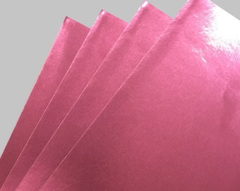 May include: Four sheets of metallic pink paper, stacked on top of each other.