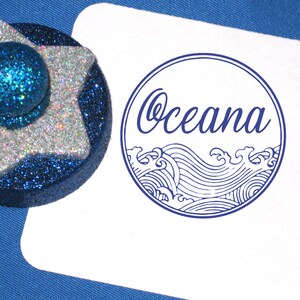 Puede incluir: Un sello de goma azul y blanco con la palabra "Ocean" y un dise&ntilde;o de ola estilizado.