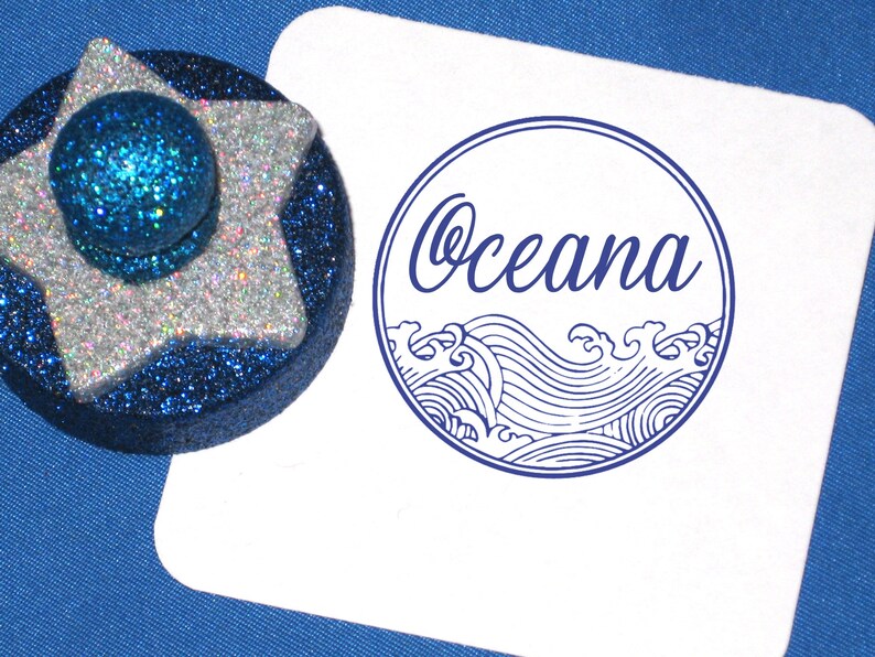 Puede incluir: Un sello de goma azul y blanco con la palabra "Ocean" y un dise&ntilde;o de ola estilizado.