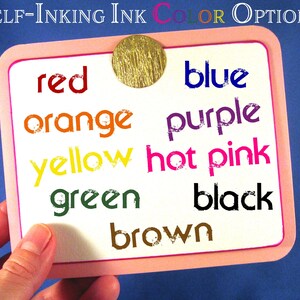 Puede incluir: Una tarjeta blanca con un borde rosa enumera los colores de tinta autoentintable: rojo, naranja, amarillo, verde, marr&oacute;n, azul, morado, rosa intenso y negro. La tarjeta se sostiene en una mano.