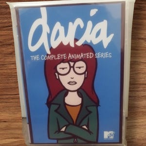 Puede incluir: Un juego de DVD sellado de la serie animada "Daria". La portada presenta el título del programa en escritura blanca sobre una ilustración de Daria Morgendorffer con cabello rojo, gafas y una chaqueta verde. También es visible el texto "THE COMPLETE ANIMATED SERIES".