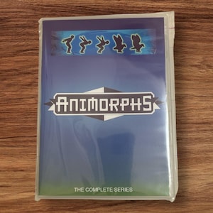 Puede incluir: Un juego de DVD precintado de Animorphs: The Complete Series. La portada es azul con el logotipo de Animorphs en blanco y una fila de siluetas. La parte inferior de la portada dice "THE COMPLETE SERIES".