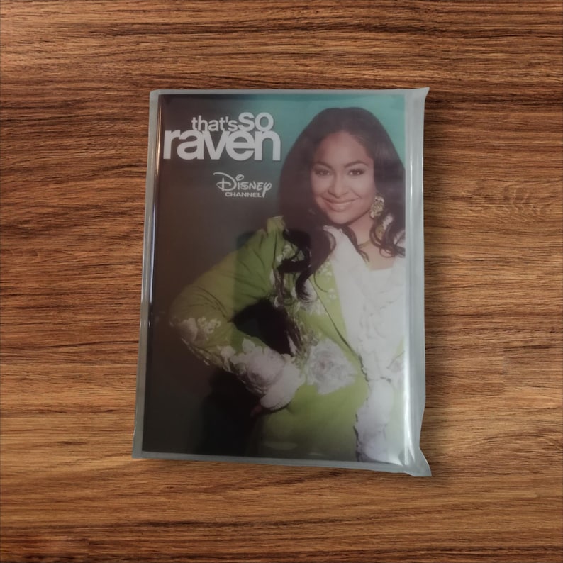 May include: A DVD of the Disney Channel show "That's So Raven" in a plastic sleeve. The cover features Raven-Symon&eacute; in a green and white outfit. The Disney Channel logo is visible.