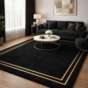 Puede incluir: Una alfombra rectangular negra con dos franjas doradas en los bordes. La alfombra está en un salón con un sofá negro, una mesa de centro de mármol blanco y una lámpara de araña dorada.