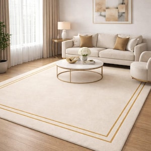 Pode incluir: Um tapete retangular creme com uma borda dourada em uma sala de estar. O tapete é colocado em um piso de madeira e o quarto possui um sofá, cadeiras e uma mesa de centro. O quarto é bem iluminado com luz natural.