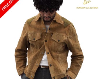 May include: A brown suede jacket with olive green shoulder accents. The jacket has two chest pockets and a button-up front. The model is wearing a white shirt and gray pants. The jacket is from London Lux Leather.