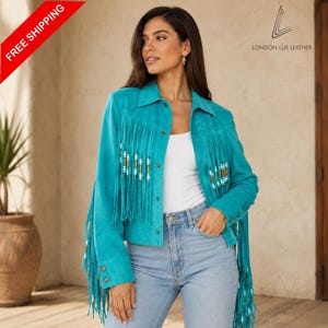 May include: A bright turquoise suede jacket featuring long fringe detailing on the front and sleeves, accented with small cylindrical beads. The jacket has a classic collar, button-front closure, and buttoned cuffs, branded with the London Lux Leather logo.