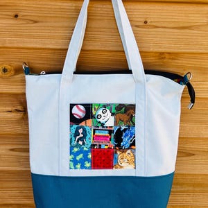 May include: White tote bag with a teal bottom and white handles. A square patch features various colorful images including a baseball, panda, horse, mermaid, and cat. The patch also includes the text "NOVEL, MYSTERY, ROMANCE, NONFICTION."