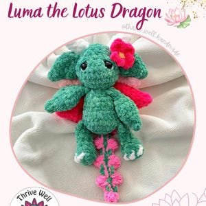 Puede incluir: Un peluche de dragón tejido a ganchillo de color verde llamado Luma the Lotus Dragon. El dragón presenta una flor rosa en la cabeza, ojos grandes y oscuros, y una cola larga con detalles en rosa. El texto Luma the Lotus Dragon es visible arriba.