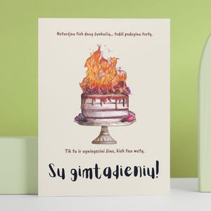 Puede incluir: Tarjeta de cumpleaños con una ilustración en acuarela de un pastel en llamas. El pastel está sobre un soporte decorativo, con texto en escritura negra en la parte inferior que dice "¡Feliz cumpleaños!"