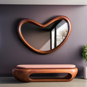 May include: A wall-mounted mirror with a smooth, dark wood frame shaped like an irregular, rounded heart. Below the mirror sits a low, elongated bench featuring a matching dark wood base with a central open cutout and a soft, light pink cushion.