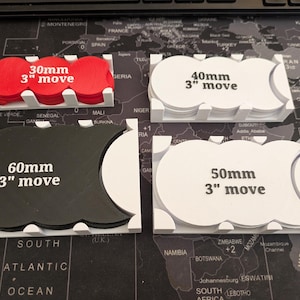 K&ouml;nnte beinhalten: Vier Spielbewegungs-Tabletts in Wei&szlig;, Rot und Schwarz. Jedes Tablett enth&auml;lt kreisf&ouml;rmige Token mit dem Text "3" move" und den Ma&szlig;en 30 mm, 40 mm, 50 mm und 60 mm.