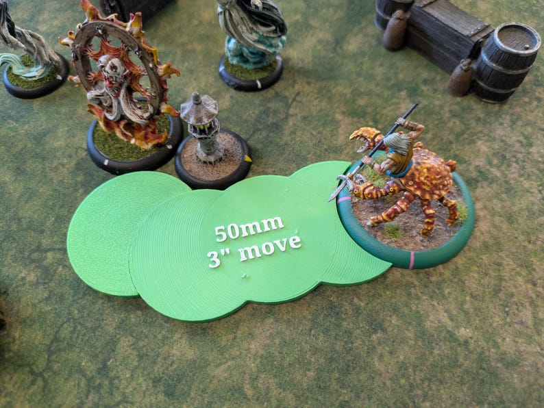 K&ouml;nnte beinhalten: Eine Tabletop-Spielszene mit Miniaturfiguren und gr&uuml;nen Bewegungsvorlagen. Die Vorlagen zeigen den Text "50mm 3" move". Eine krabbenartige Kreaturenfigur befindet sich im Vordergrund, mit anderen Figuren und Gel&auml;nde im Hintergrund.