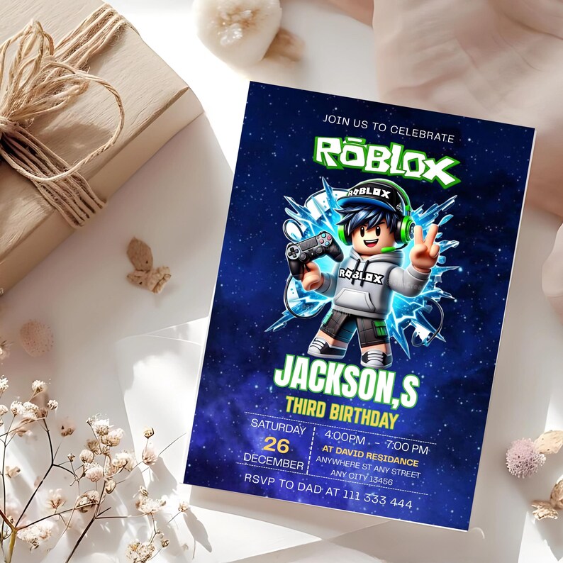 May include: A rectangular birthday invitation card featuring a dark blue space background with a Roblox character wearing a grey hoodie, green headset, and holding a game controller. The text includes JOIN US TO CELEBRATE, ROBLOX, JACKSON,S THIRD BIRTHDAY, and event details.